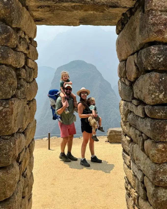 Familia feliz tomando una foto grupal en Machu Picchu en un día soleado