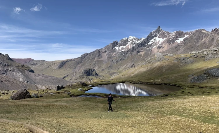 A hiker walking near an Ausangate lagoon at high altitude in Cusco Peru