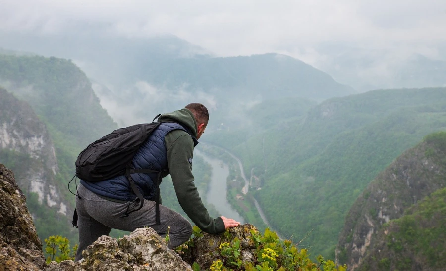 A traveler on a rocky overlook above misty Andean mountains near Choquequirao, Peru, evoking the high elevation trek environment.