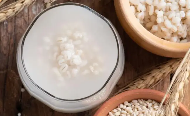 Barley water next to barley grains.