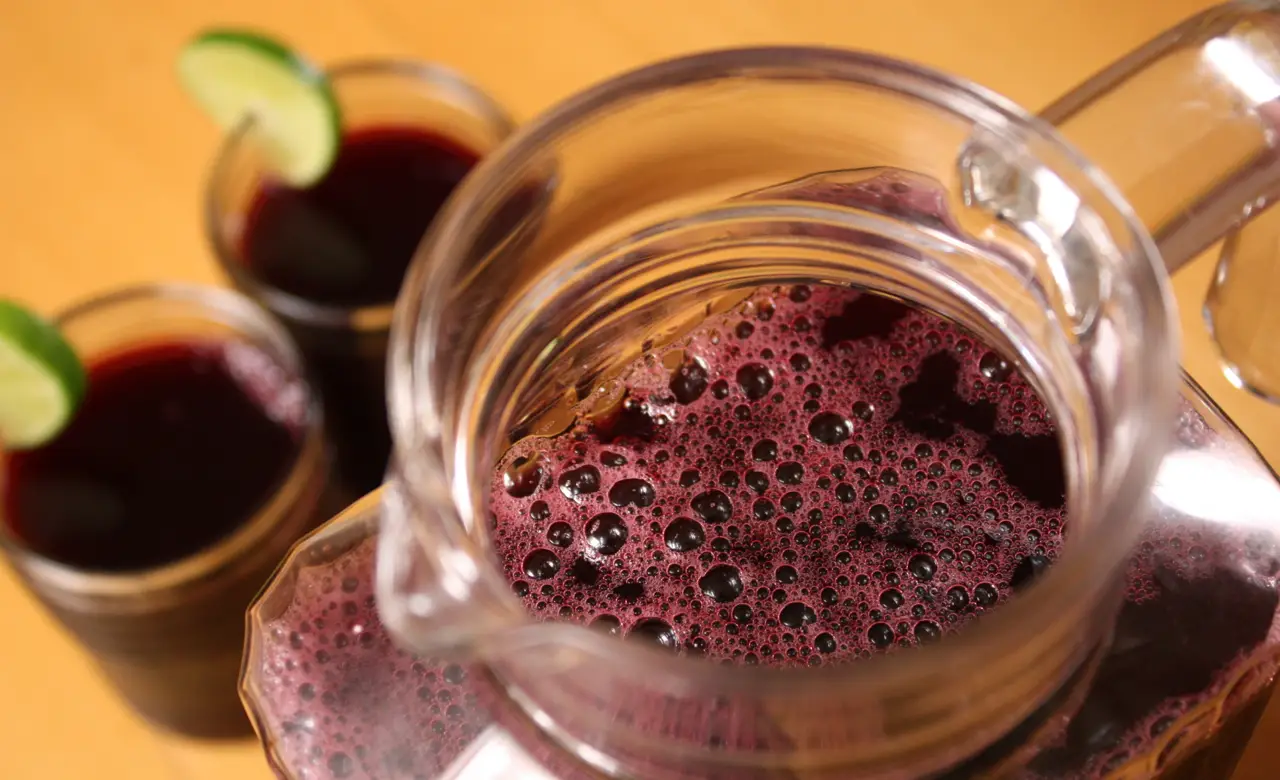 Chicha morada, Peruvian drink made with purple corn served in pitcher and glass glasses with a slice of lemon.