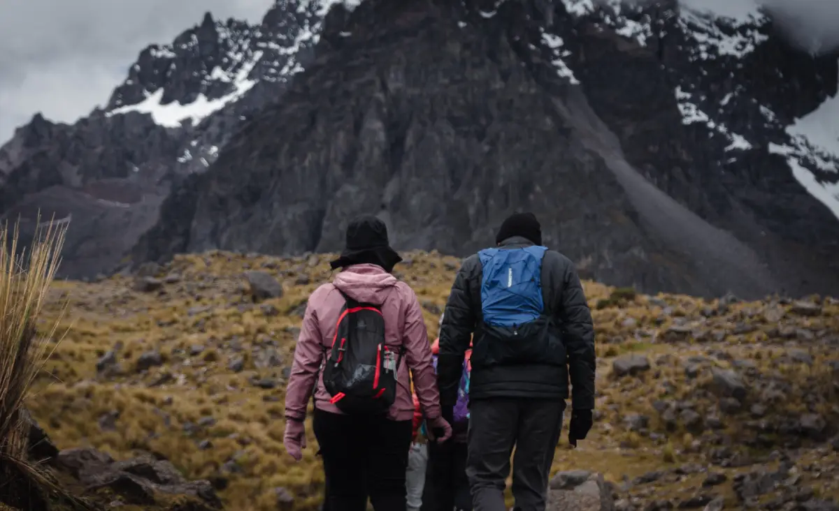Una pareja tomada de la mano caminando en la ruta de la montaña Ausangate.