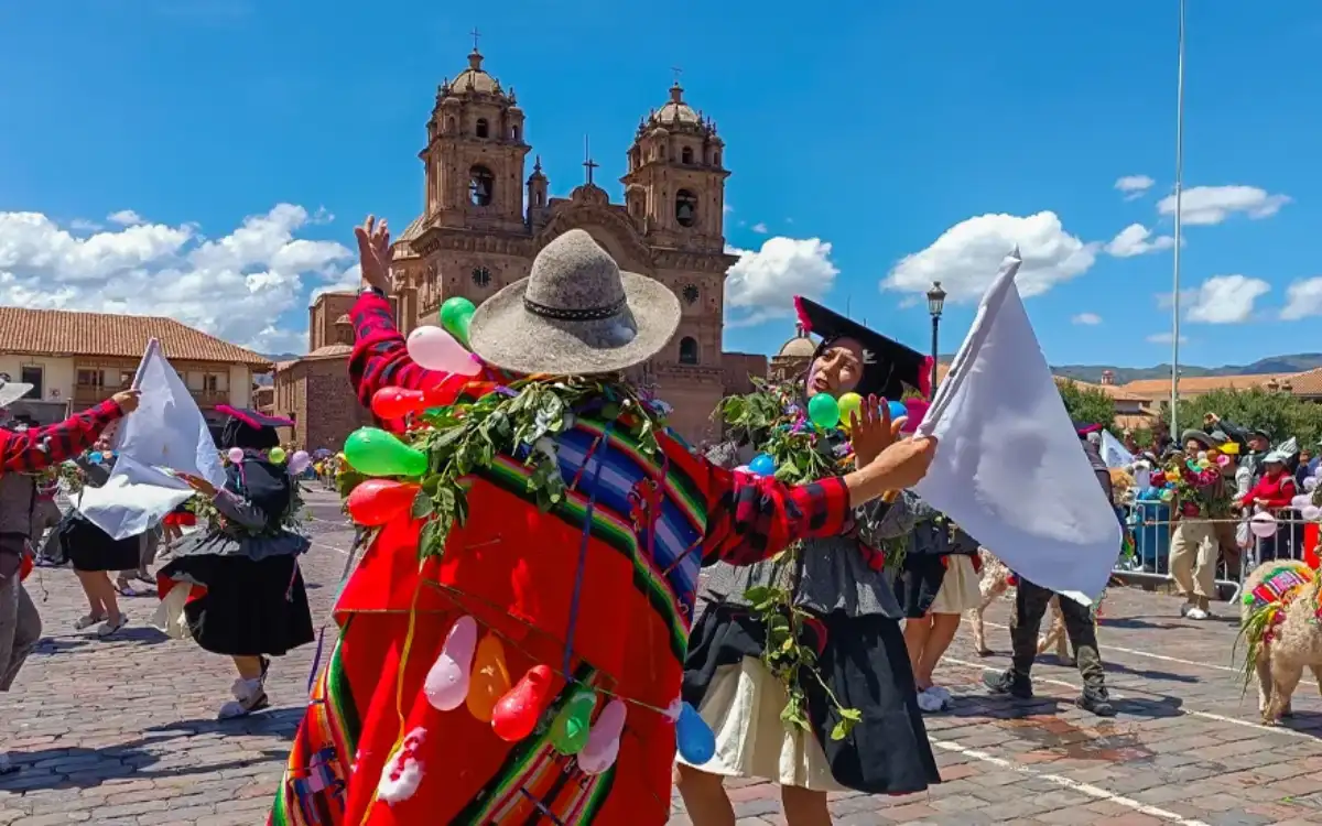 Danzantes tradicionales en Cusco, Perú, con trajes coloridos, público y una iglesia histórica al fondo durante una festividad local.