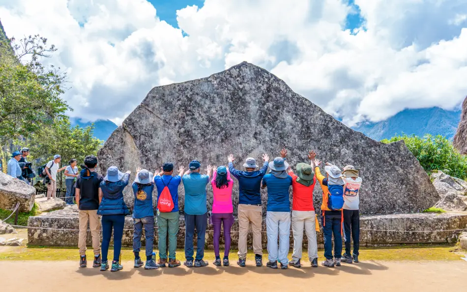 Viajeros cerca de la Roca Sagrada en Machu Picchu con gran formación de piedra