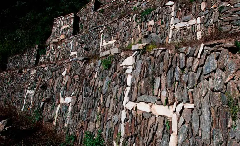 White stone llama figures embedded in dark terrace wall at Choquequirao ruins near Cusco, Peru, overlooking Apurímac canyon, alternative to Machu Picchu.