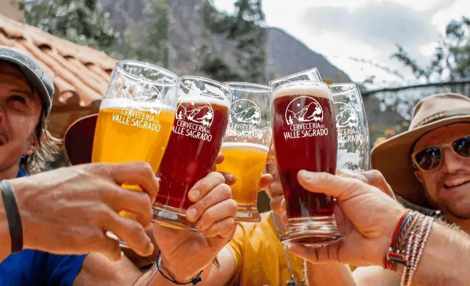 Friends sharing a craft beer in Cusco on a sunny day.