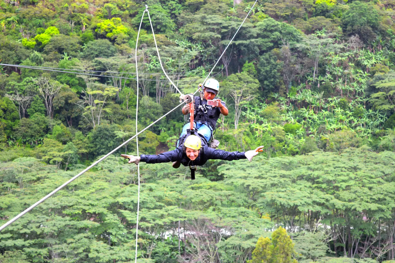 Traveler doing zipline near Santa Teresa during the Inca Jungle Trek, flying over the green valley with safety gear.