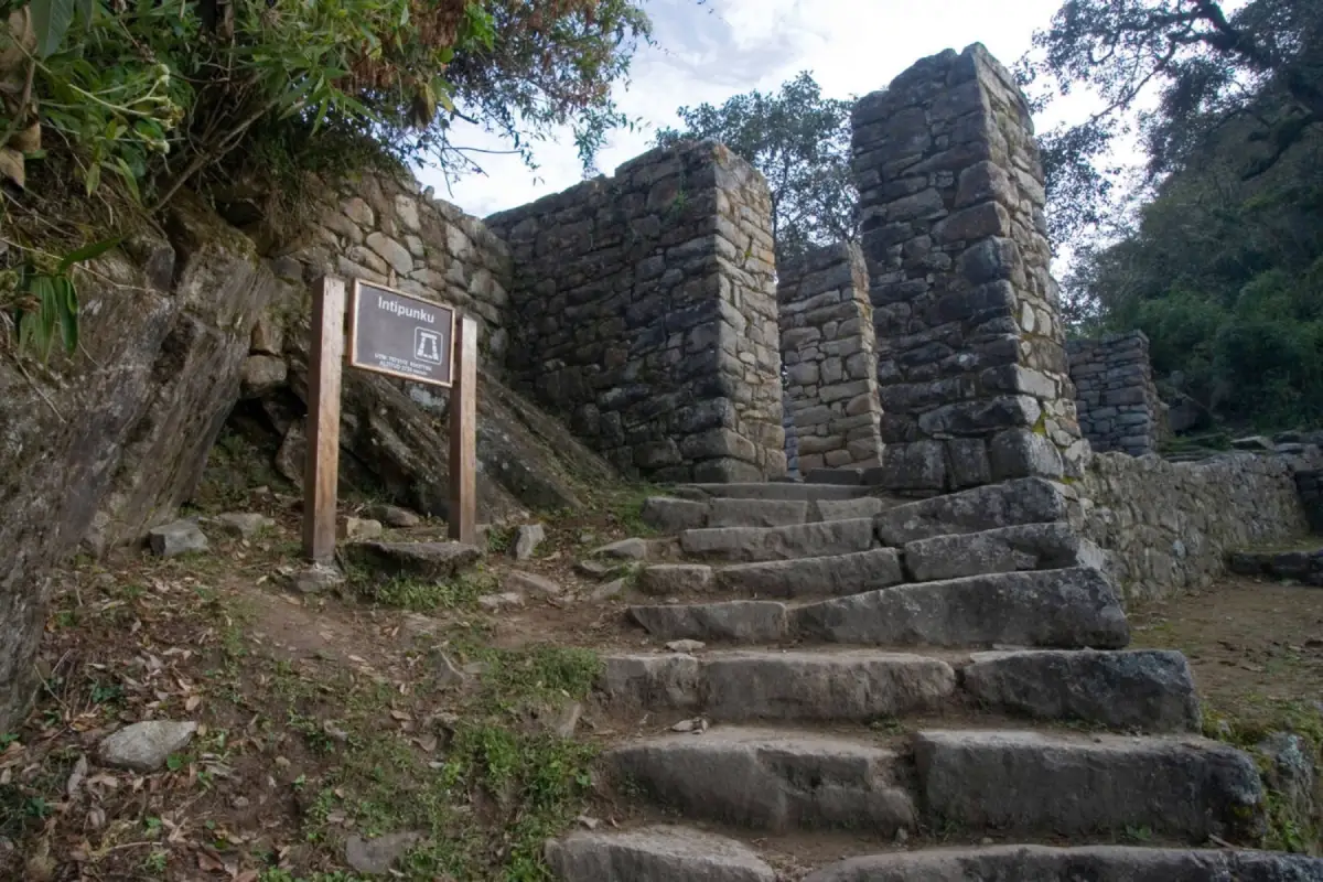 Intipunku o Puerta del Sol en el Camino Inca cerca de Machu Picchu, con escalinatas de piedra, muros incas y señalización del sitio arqueológico.