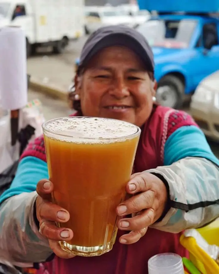 Juice vendor with a smile extending the drink to the customer.