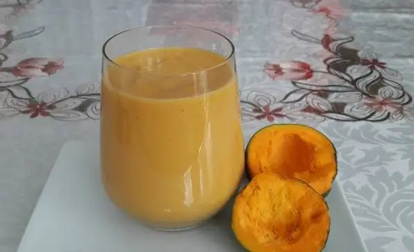 Lúcuma juice in a glass glass next to lúcuma fruit.