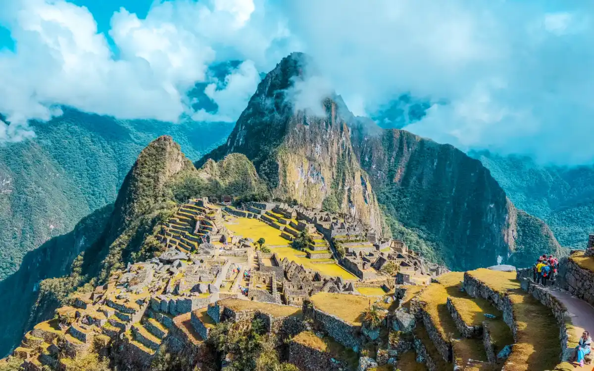Vista panorámica de Machu Picchu con terrazas y la montaña Huayna Picchu bajo nubes, Cusco, Perú, destino icónico de viaje.