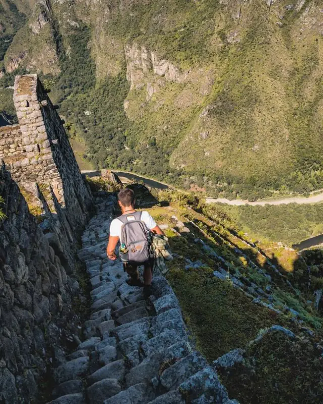 Man descending steep stone stairs at Machu Picchu.