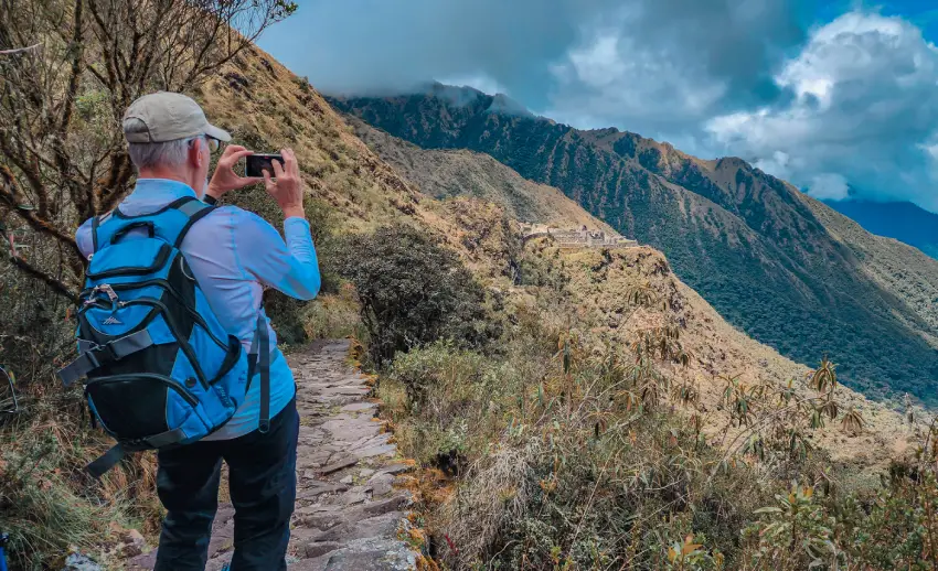 Señor de mochila azul tomándole foto a las montañas.