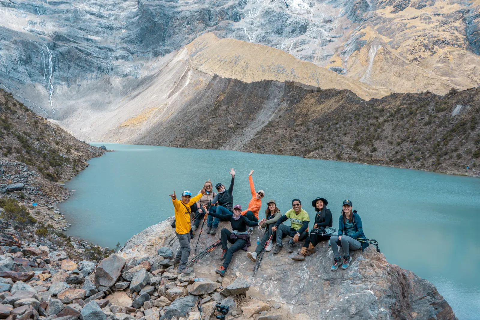 Group of hikers resting above turquoise Humantay Lake during the early section of the Salkantay Trek.
