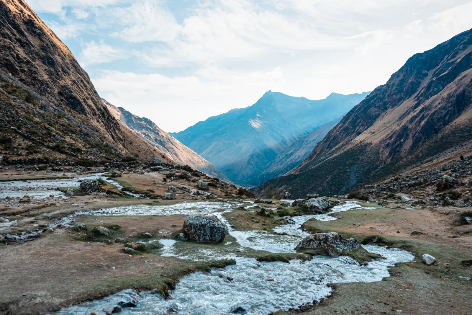 High Andean valley with glacial streams, rocky terrain, and mountain views along the Salkantay Trek.