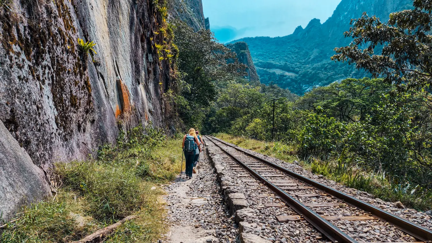 Hikers walking beside the railway on the Hidroelectrica route toward Aguas Calientes.