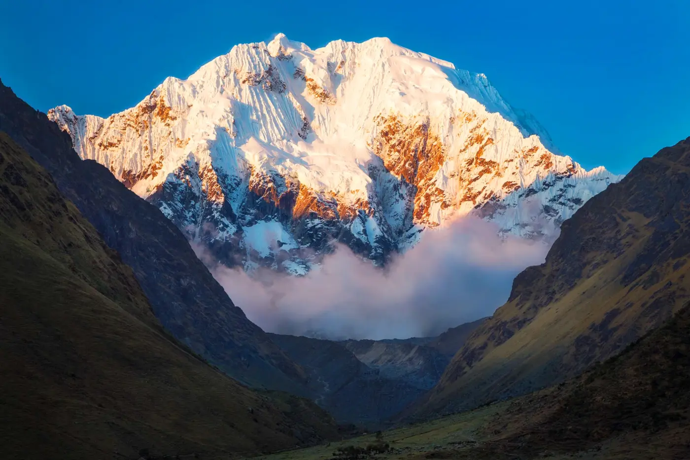Sunlit view of Salkantay mountain glowing above the valley at sunrise.