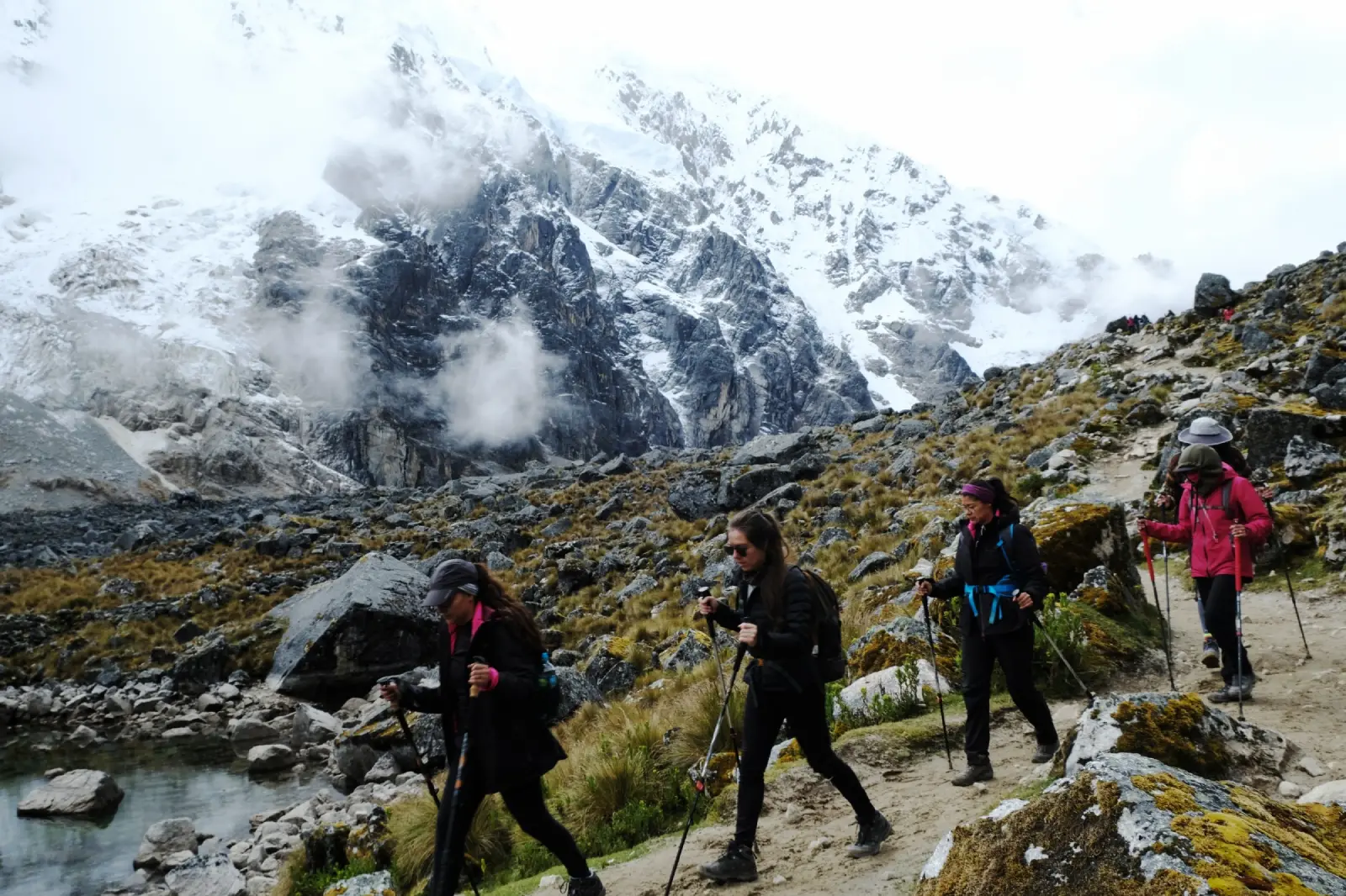 Trekkers walking along a high-altitude trail with Salkantay mountain rising in the background.