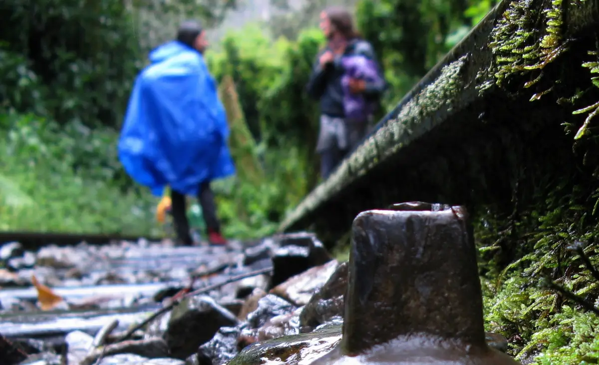Silueta de dos personas con impermeables, caminando hacia Machu Picchu.