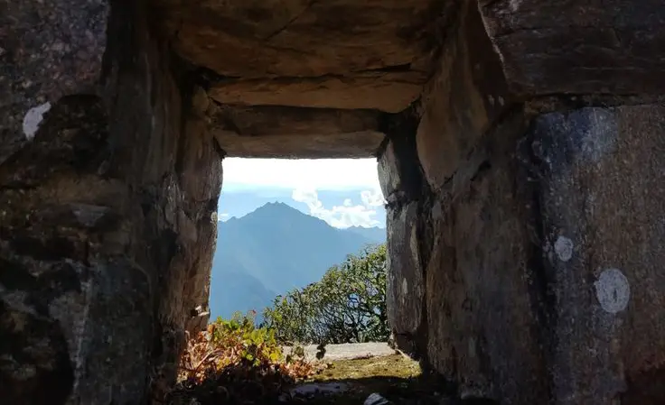 Panoramic view of Choquequirao ruins framed by a stone arch in the Vilcabamba mountains of Peru