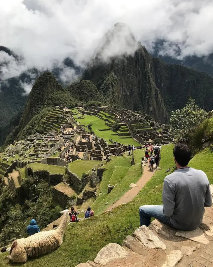 Stone paths at Machu Picchu with visitors resting near terraces and mountain views