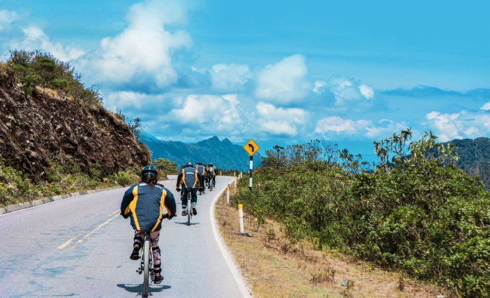 Travelers wearing helmets while cycling on the downhill road during the Inca Jungle Trek