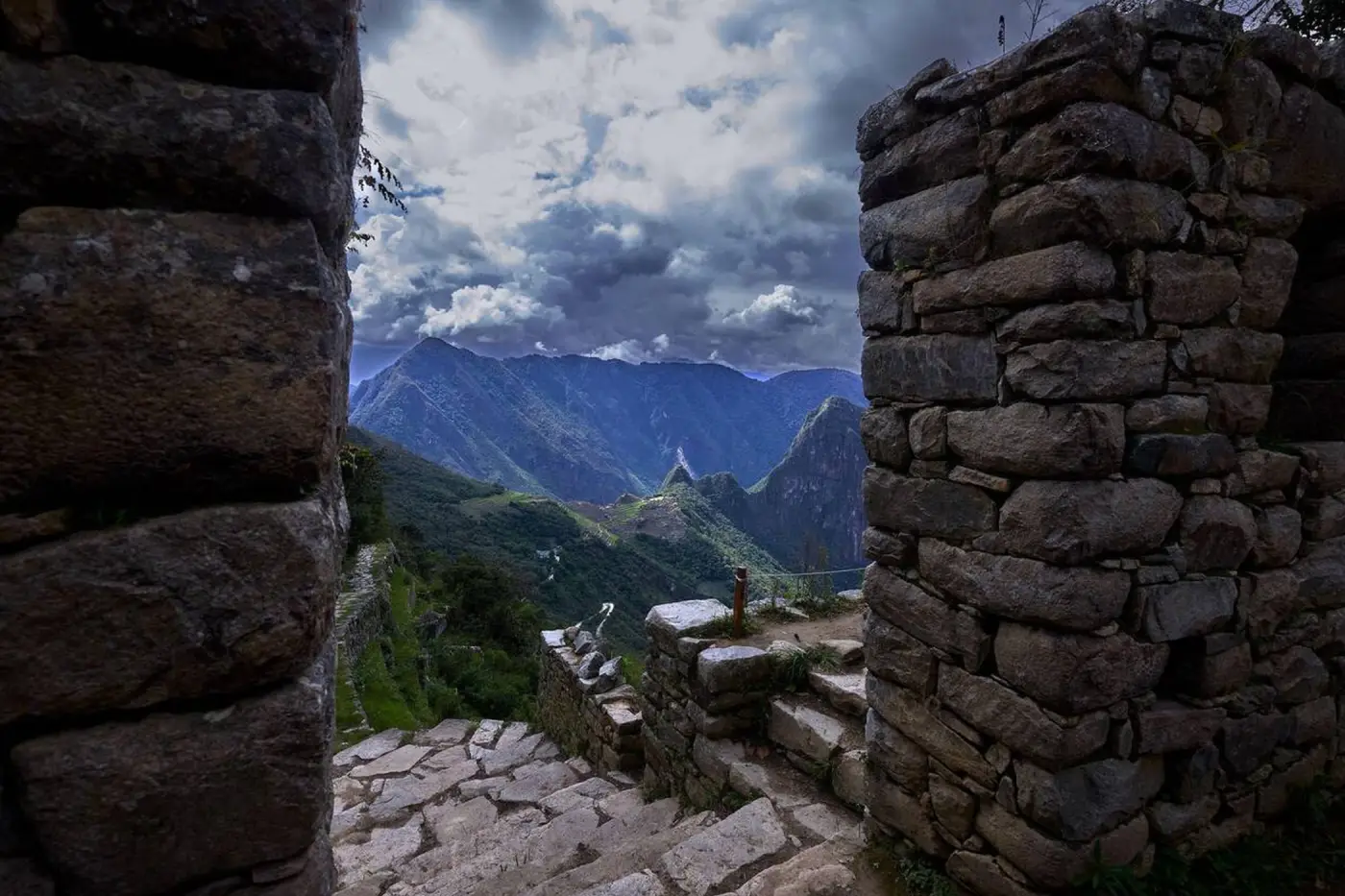 Muros de piedra y escalinatas en el Intipunku de Machu Picchu, con vistas al Huayna Picchu y al Santuario Histórico circundante.