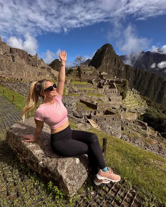 Woman smiling with her hand raised at Machu Picchu.