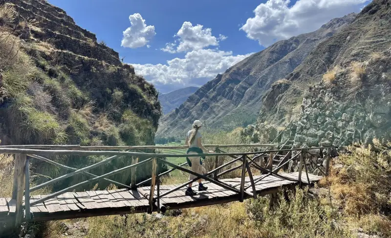 Woman walking across a wooden bridge in Pisac