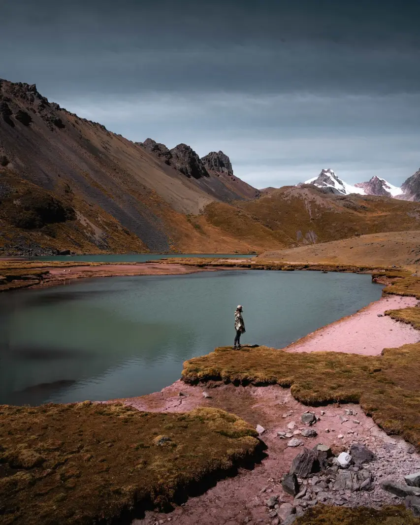 Mujer caminando en la inmensidad de la laguna y montaña de Ausangate.
