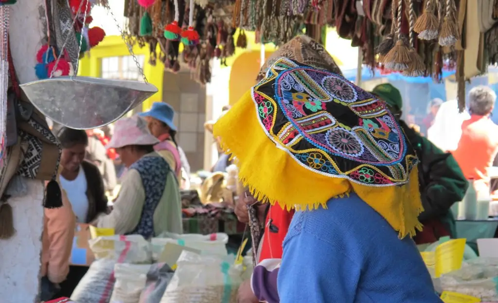 Mujer con sombrero tradicional esperando compradores en el mercado de Huancaro