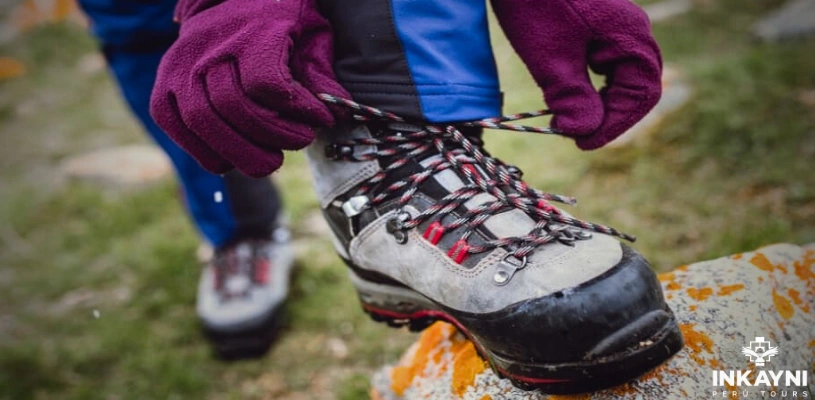 A person tying the laces of their trekking shoe.