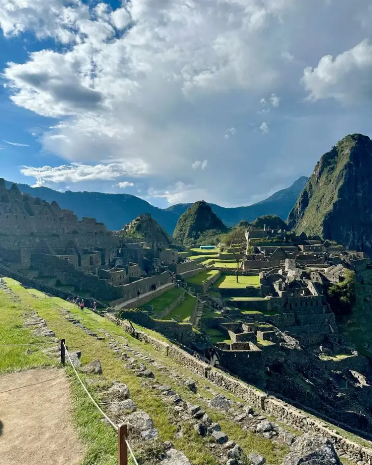 aguas calientes to machu picchu citadel clouds blue sky mountain inca path stones green horizon