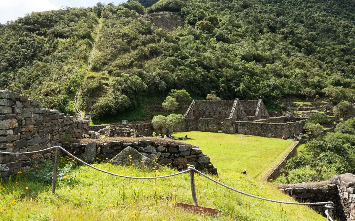 Plaza principal y estructuras de piedra inca en Choquequirao rodeadas de vegetación andina en el cañón del Apurímac, Perú.