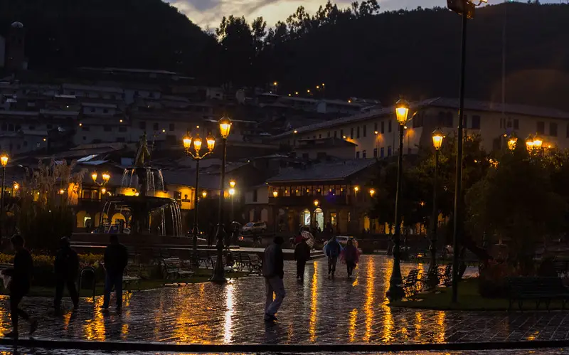 Anochecer en una de las plazas de Cusco, con un clima frío y las luces de los faroles iluminando el lugar. Temporada de lluvias en Cusco