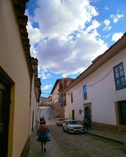 Señora caminando por las calles de Cusco con el cielo azul y despejado