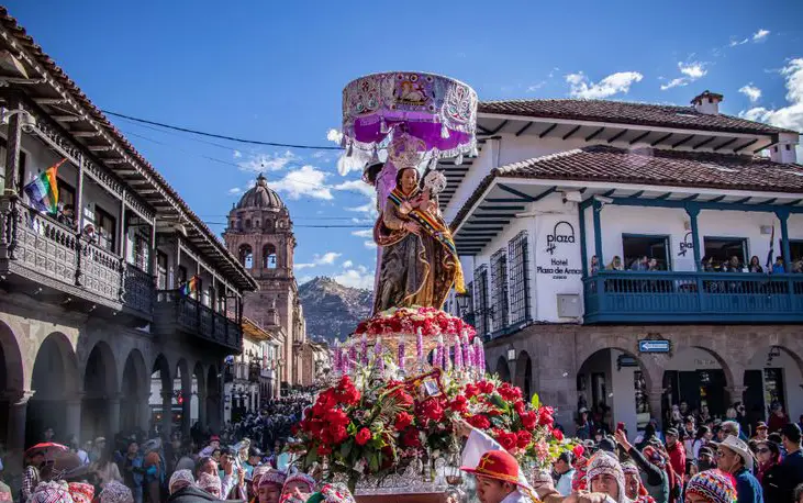 Procesión de la Virgen de Natividad (Corpus Christi) cruzando la calle en un día soleado.