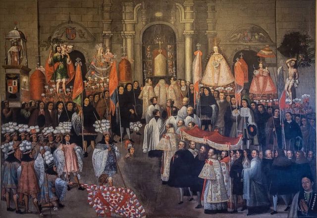Peruvian colonial painting showing Corpus Christi religious procession in Cusco, featuring ecclesiastical authorities, indigenous nobility, saints on litters, floral carpets, church interior with stone arches and crowd of worshippers in period dress