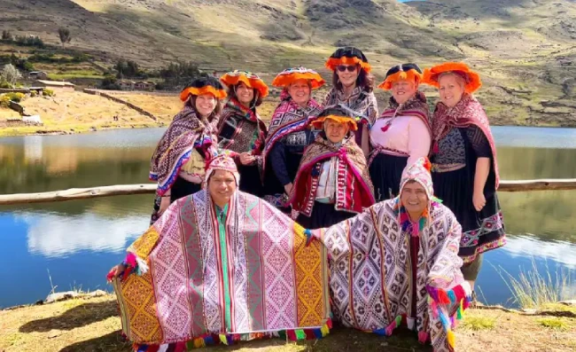 Grupo de visitantes con pobladores del Parque de la Papa cerca de Pisac, Cusco, Perú, con vestimenta tradicional en un entorno rural andino.