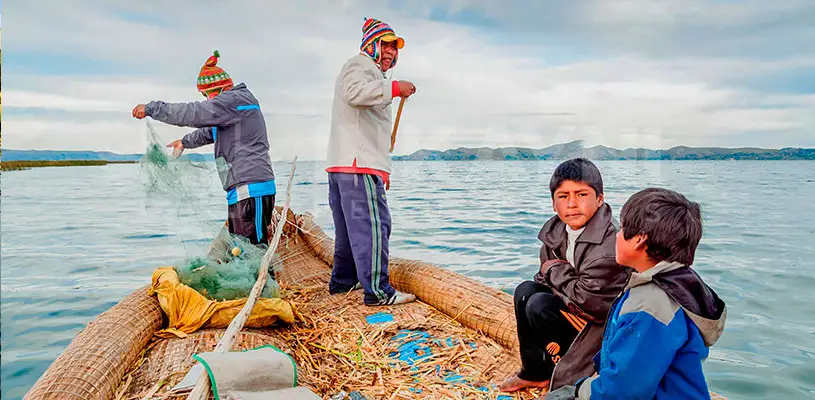 Dos niños y dos adultos disfrutando de una día en balzas sobre las aguas del lago Titicaca.