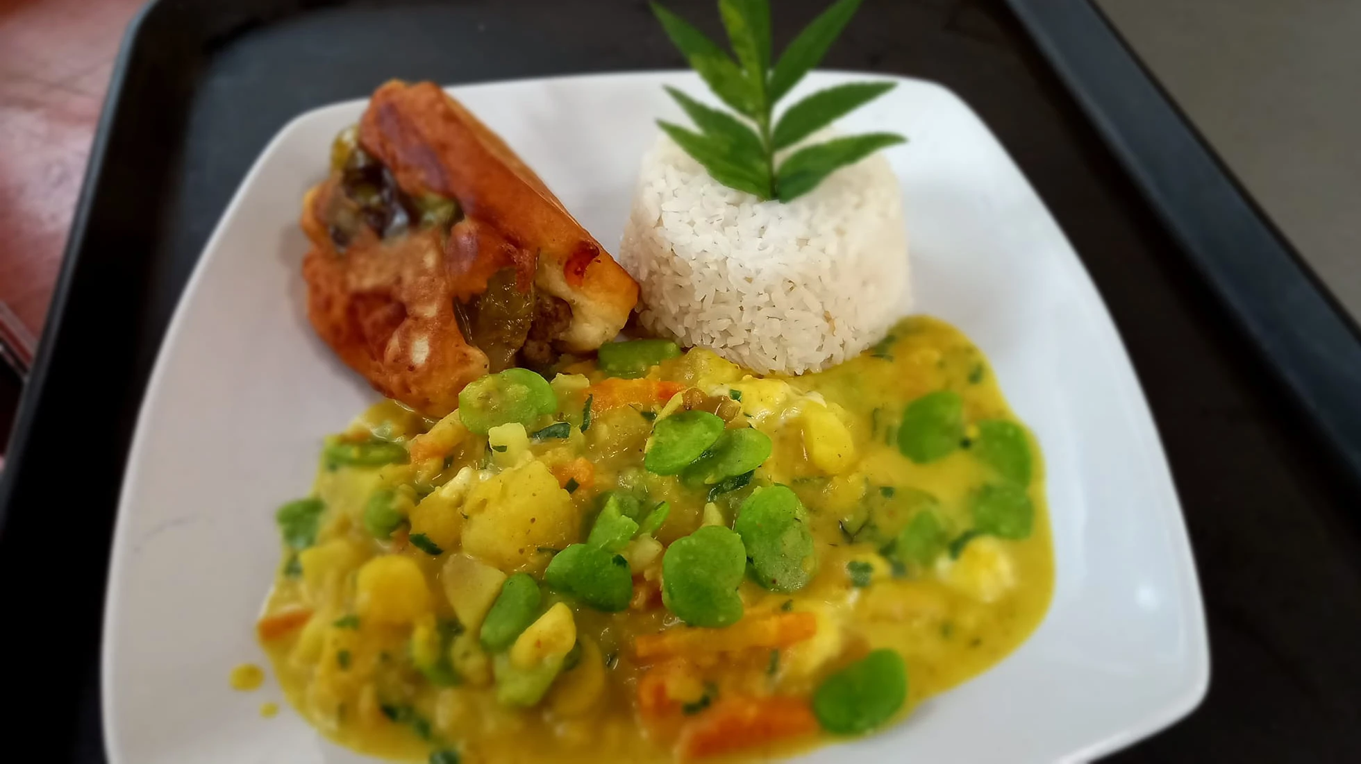 Plate of Cusco-style kapchi de habas, a creamy fava bean and potato stew, served with white rice and a stuffed pepper on the side.