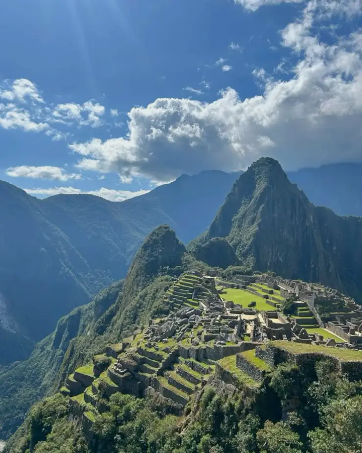 Ciudad sagrada de Machu Picchu rodeada de montañas verdes, nubes y paisaje andino