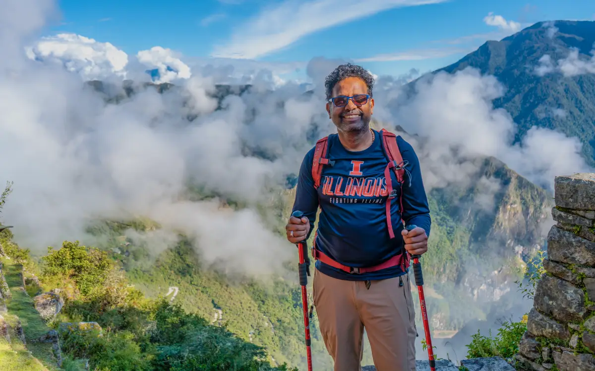 Viajero cerca del Intipunku, Puerta del Sol, con nubes, vegetación y paisaje de montaña sobre Machu Picchu
