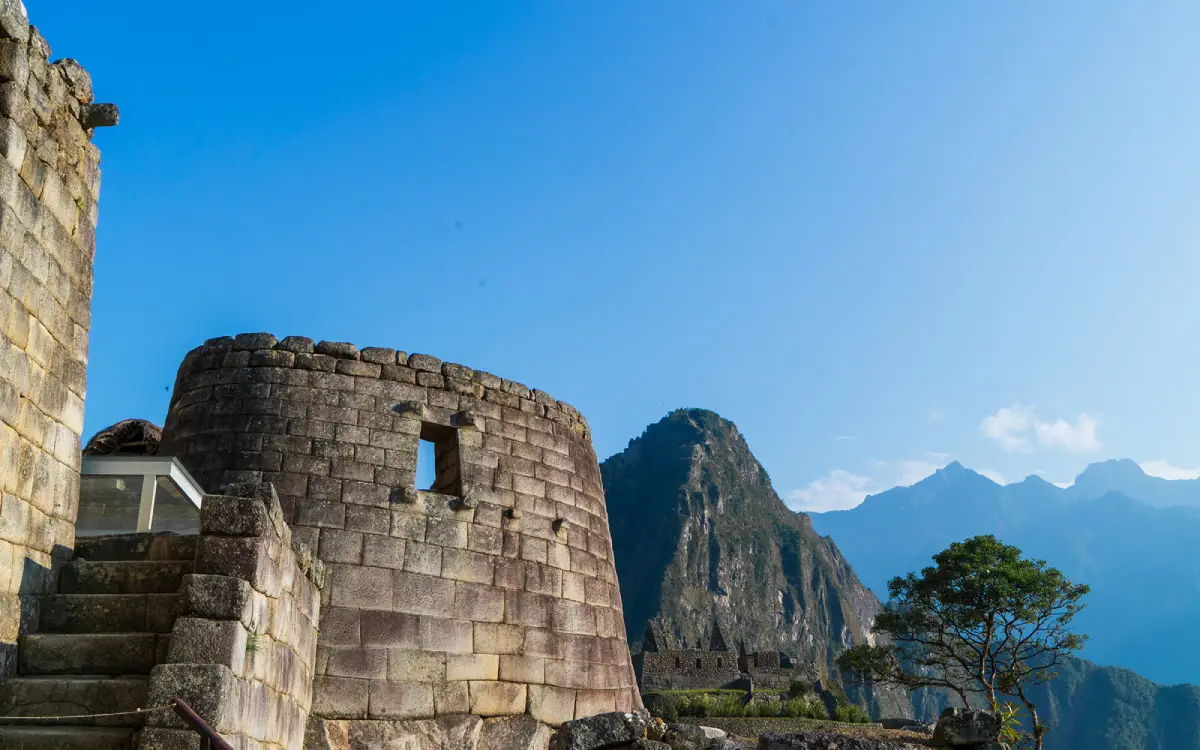 Templo del Sol en Machu Picchu con muros de piedra, escalinatas, montaña y árboles