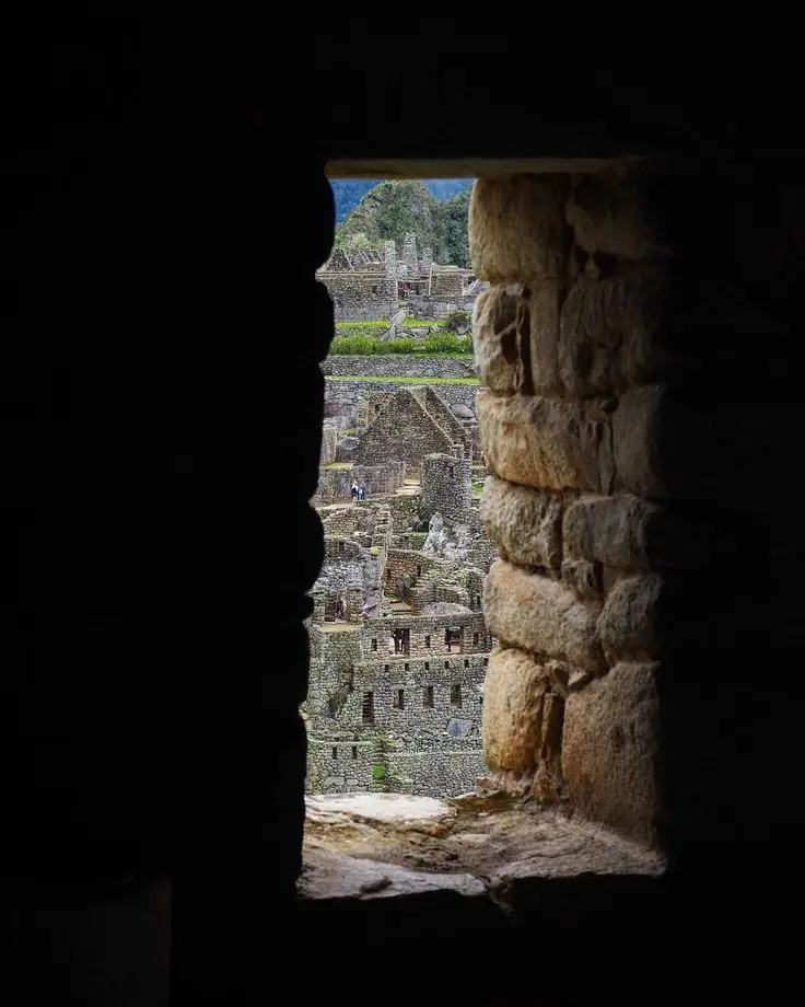 Machu Picchu visto a través de una ventana de piedra con luz y sombras