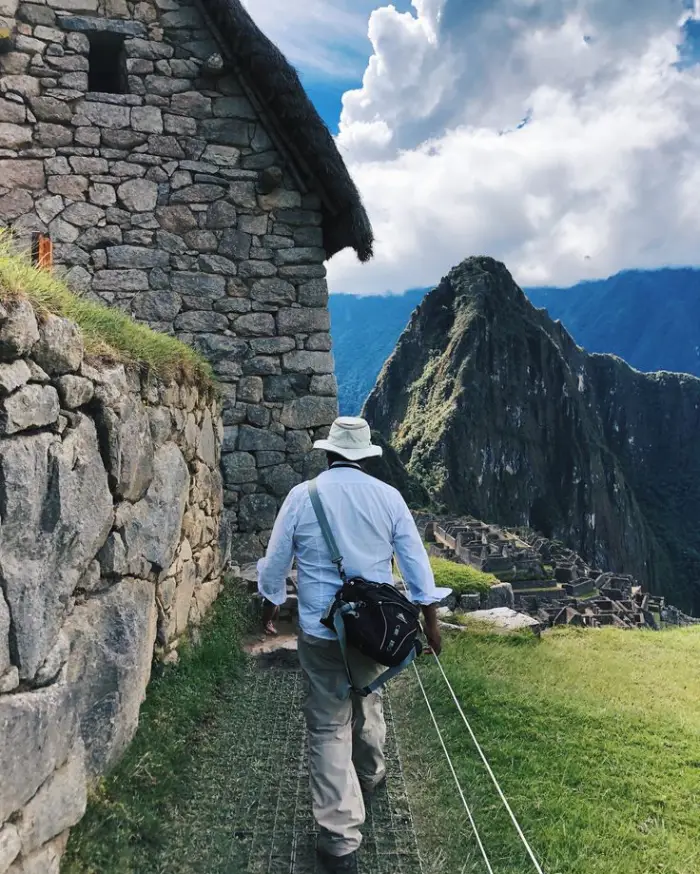 exploring Machu Picchu stone houses sky cloud man tourist green vegetation