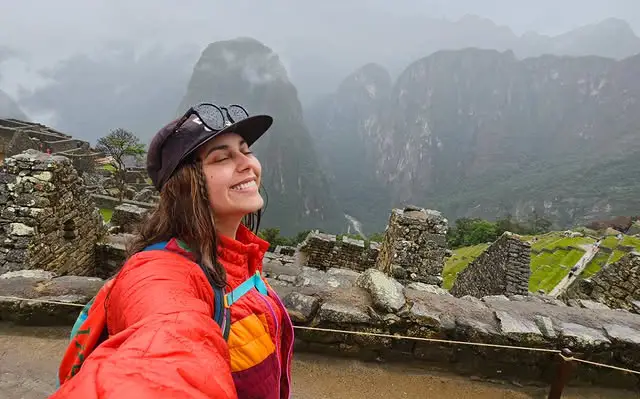machu picchu bajo la lluvia turista extranjera temporada de lluvia casaca roja lentes gorro neblina frío cusco ciudadela
