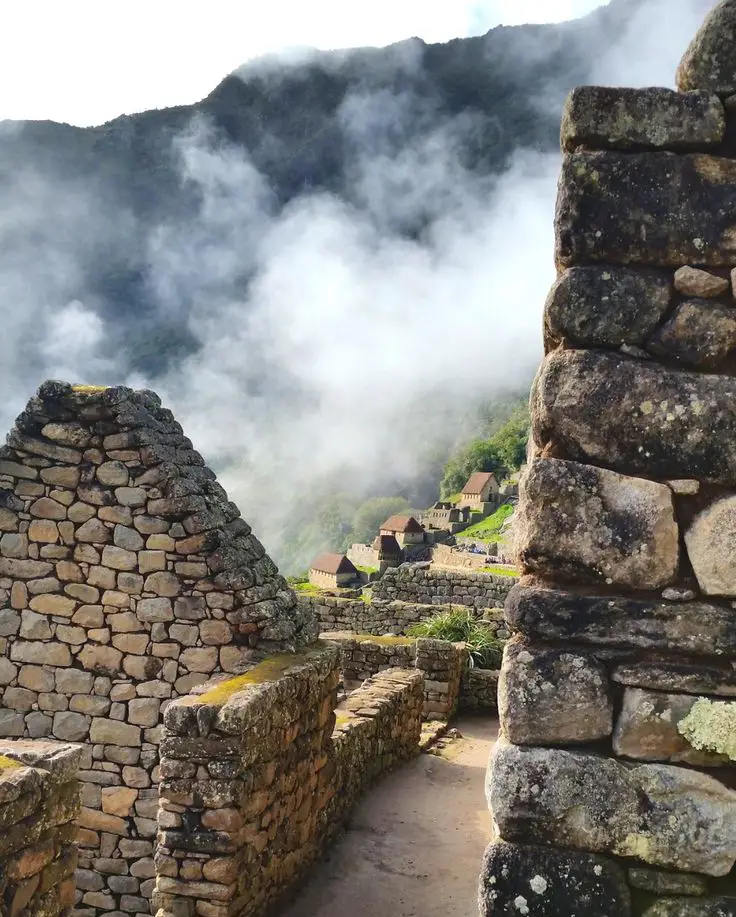 Muros de piedra de Machu Picchu con neblina y nubes durante un momento tranquilo