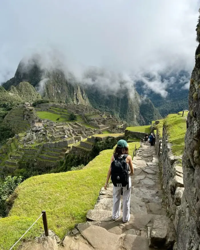 exploring Machu Picchu woman cusco tourist green clouds mist mountain stone sanctuary