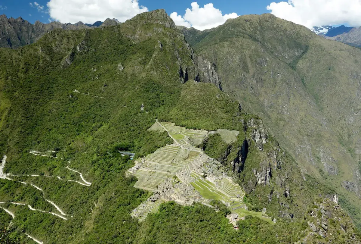 View from the Huayna Picchu summit toward Machu Picchu Mountain, the archaeological site terraces, and the mountain surroundings of the sanctuary.